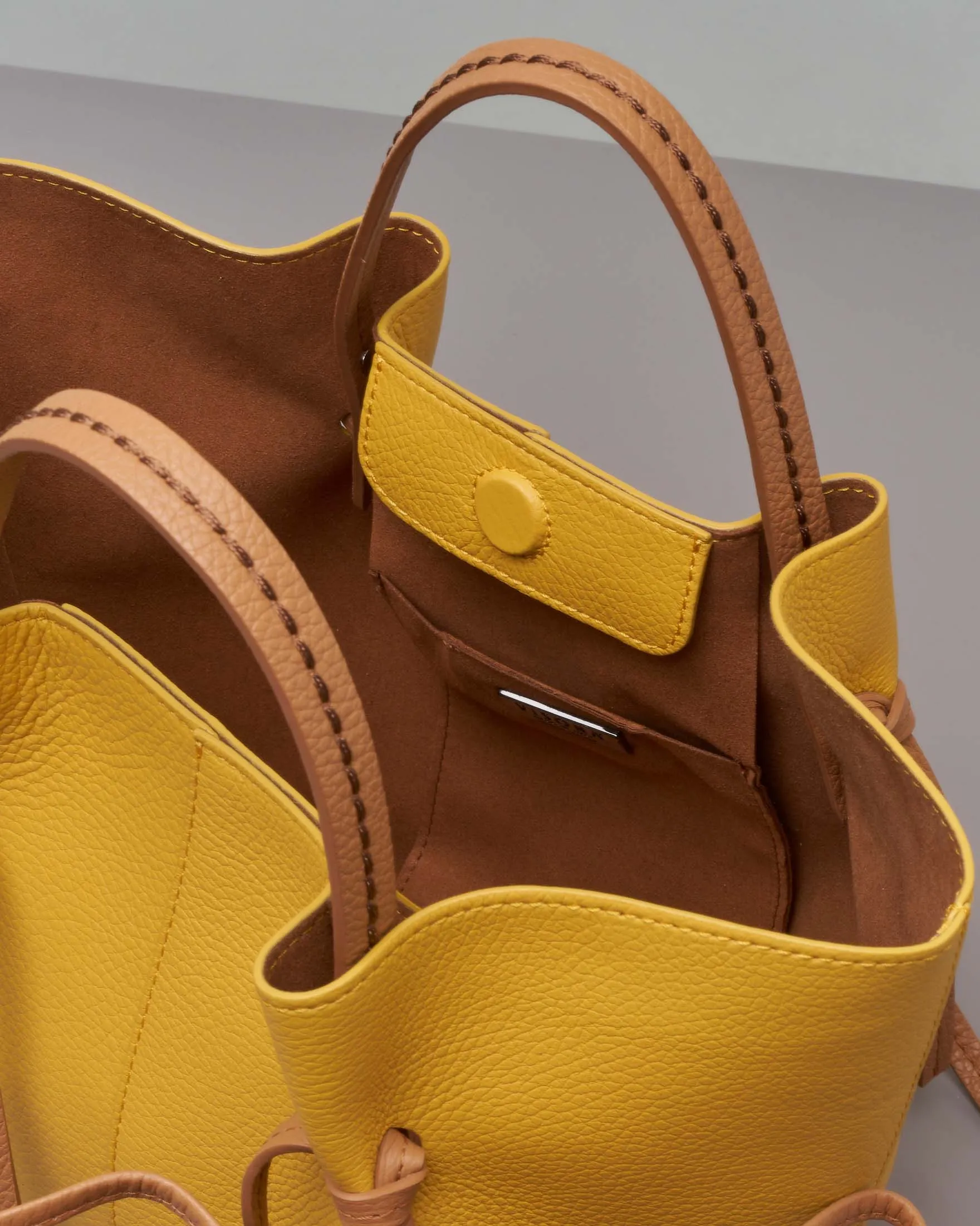 Borsa a mano gialla in pelle martellata con manici a contrasto e pochette color cuoio